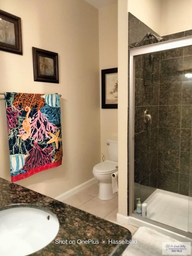 bathroom featuring a sink, tile patterned flooring, toilet, baseboards, and a shower stall