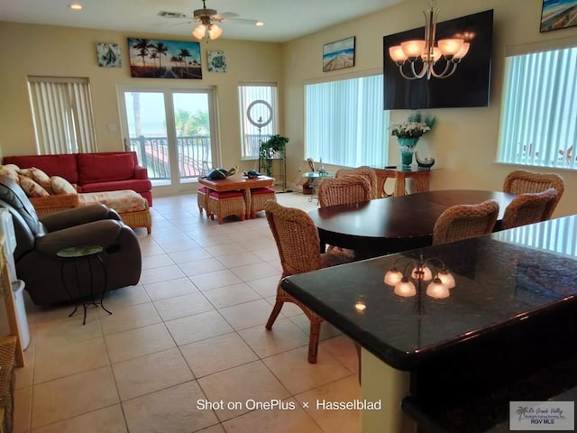 dining area featuring light tile patterned flooring, visible vents, and ceiling fan with notable chandelier