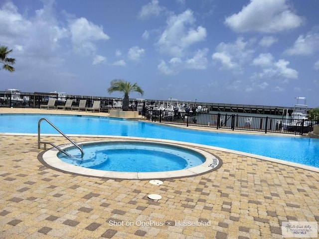 community pool with fence, a patio, and a hot tub