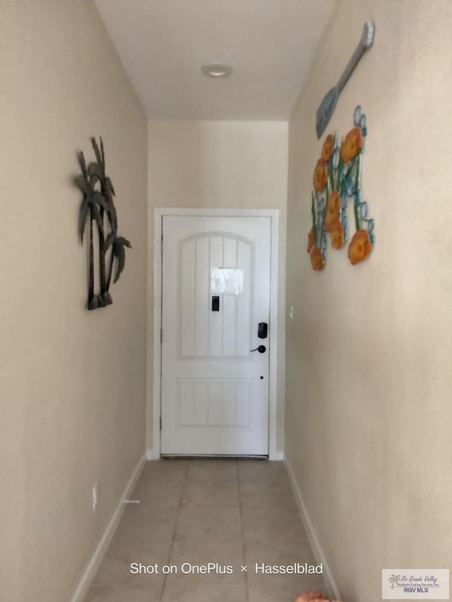 doorway featuring light tile patterned flooring and baseboards