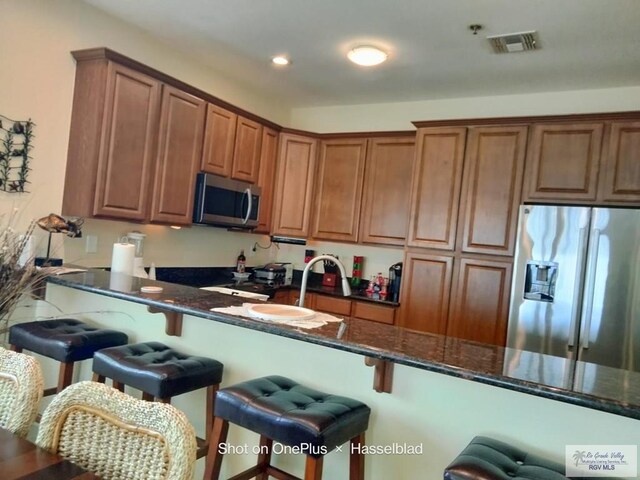 301 E Houston St Unit 1201, Port Isabel, TX 75052 - kitchen featuring dark stone counters, a breakfast bar area, stainless steel appliances, and visible vents
