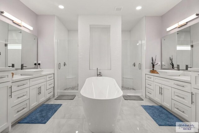 31689 E Jardin E, Los Fresnos, TX 78566 - bathroom featuring a shower stall, two vanities, a freestanding tub, marble finish floors, and recessed lighting