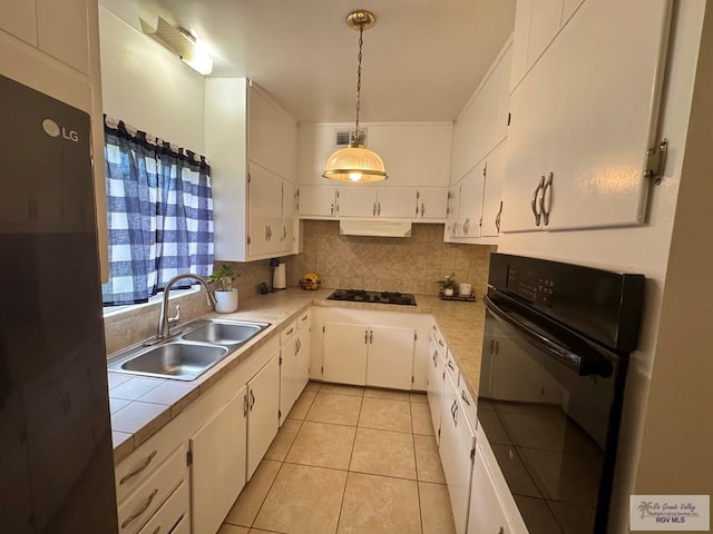1901 Martha St, Harlingen, TX 78550 - kitchen with black appliances, tasteful backsplash, white cabinets, light tile patterned floors, and decorative light fixtures