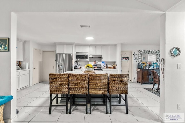 kitchen featuring appliances with stainless steel finishes, a center island, and a breakfast bar area