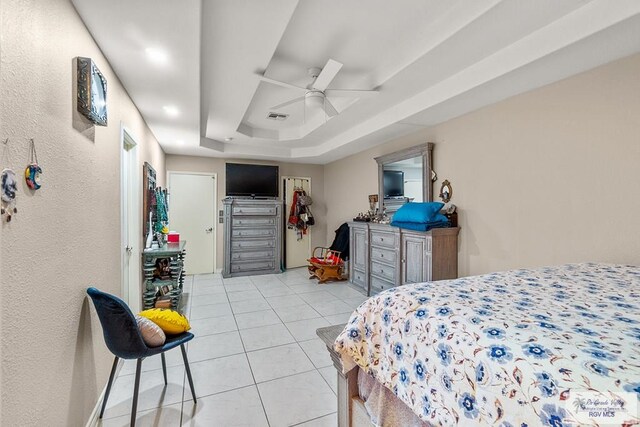 tiled bedroom featuring ceiling fan and a tray ceiling