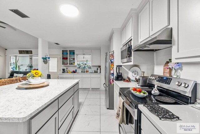 kitchen with white cabinetry, a wealth of natural light, a kitchen island, and stainless steel appliances