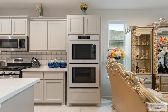 kitchen featuring decorative backsplash, stainless steel appliances, and white cabinets