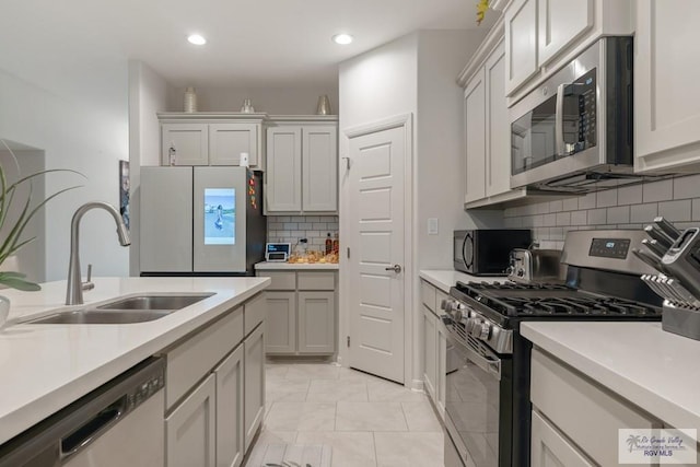 kitchen with tasteful backsplash, appliances with stainless steel finishes, light tile patterned flooring, and sink