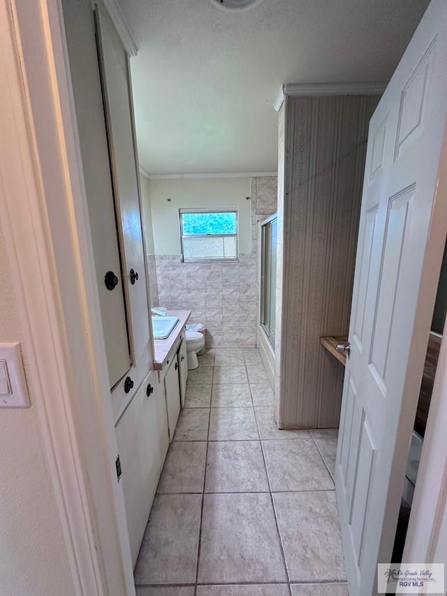 12776 State Highway 186, Raymondville, TX 78580 - bathroom with tile walls, a shower with shower door, toilet, vanity, and tile patterned floors