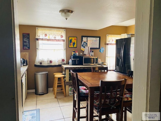 dining space featuring plenty of natural light, a textured ceiling, baseboards, and light tile patterned floors