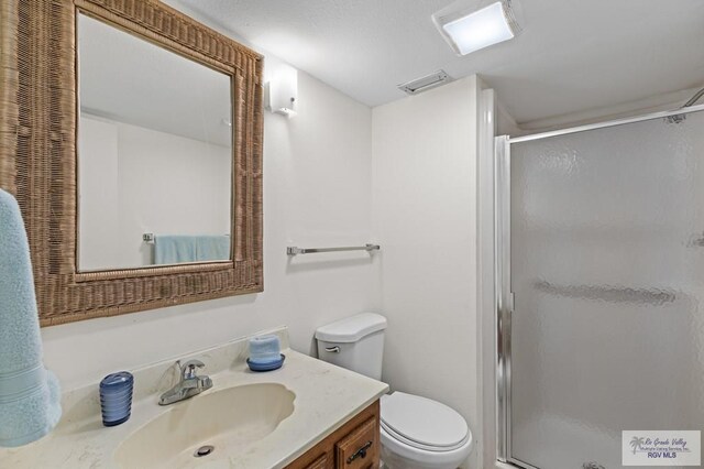 bathroom featuring vanity, an enclosed shower, and toilet