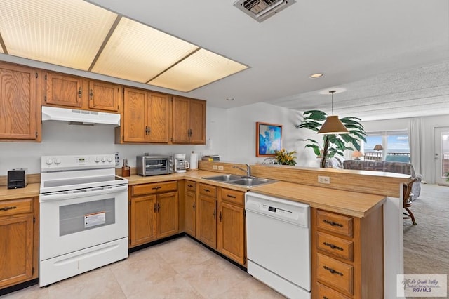 kitchen featuring sink, kitchen peninsula, light colored carpet, decorative light fixtures, and white appliances