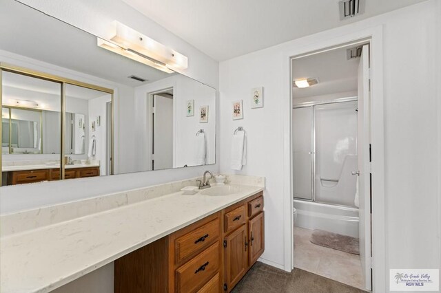 bathroom featuring tile patterned flooring, vanity, and enclosed tub / shower combo