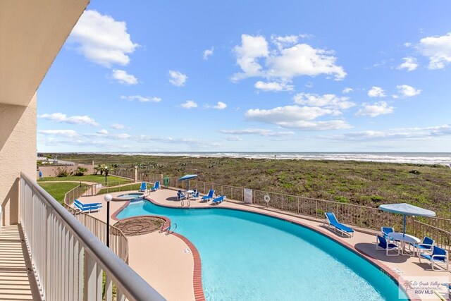 view of swimming pool with a water view and a view of the beach