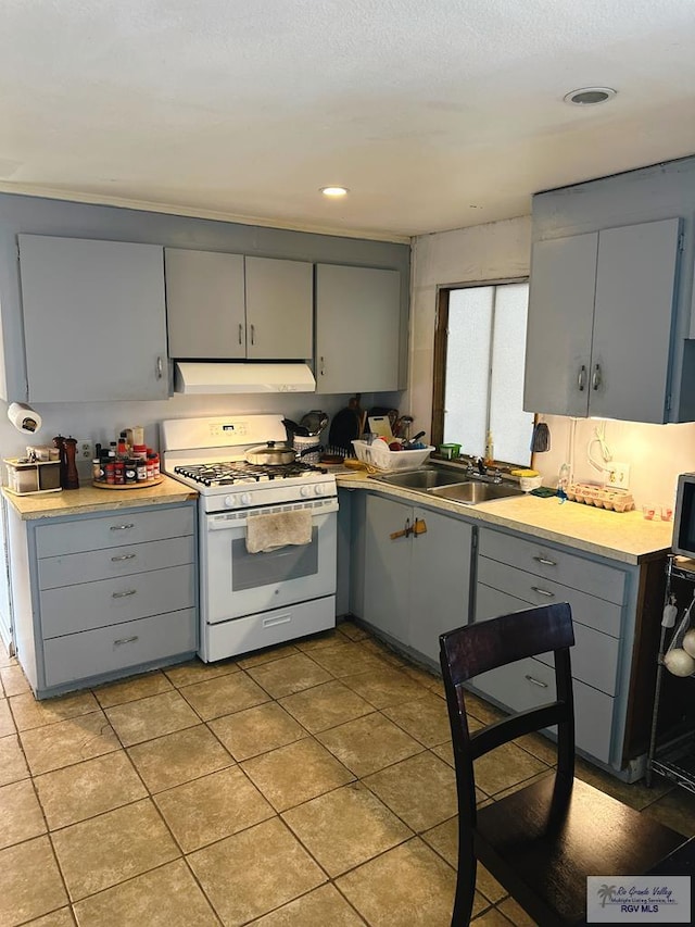 kitchen featuring gray cabinets, white gas range, sink, and light tile patterned floors