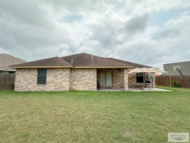 back of property with a lawn and a patio