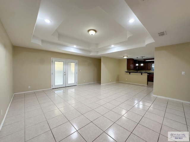 unfurnished room with french doors, a raised ceiling, and light tile patterned flooring