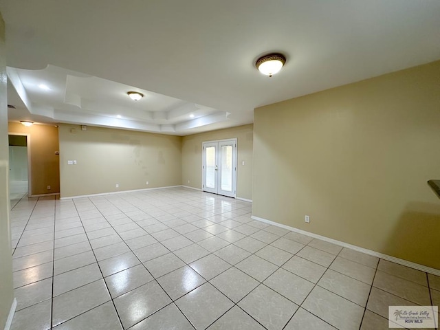 spare room featuring light tile patterned flooring, a raised ceiling, and french doors