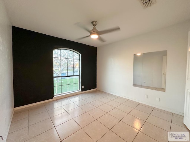 tiled spare room with ceiling fan