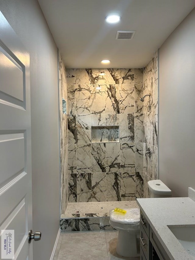 bathroom with a tile shower, vanity, and toilet