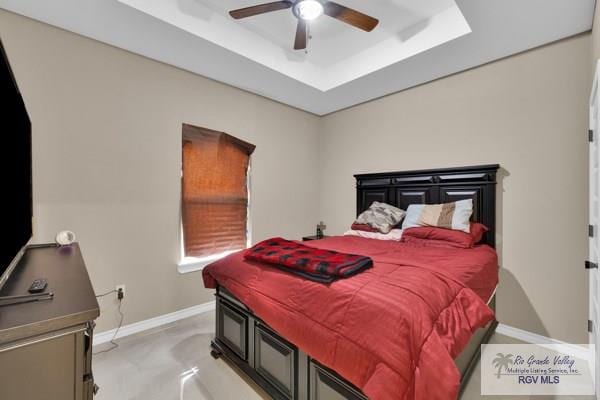 bedroom featuring ceiling fan, a raised ceiling, and baseboards