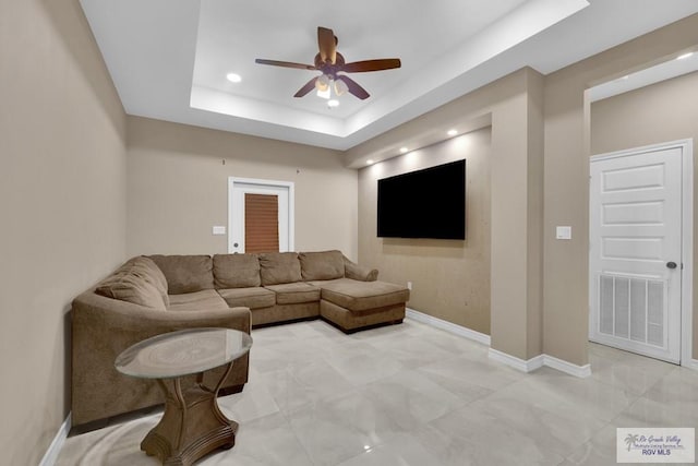 living room featuring visible vents, a raised ceiling, baseboards, and ceiling fan