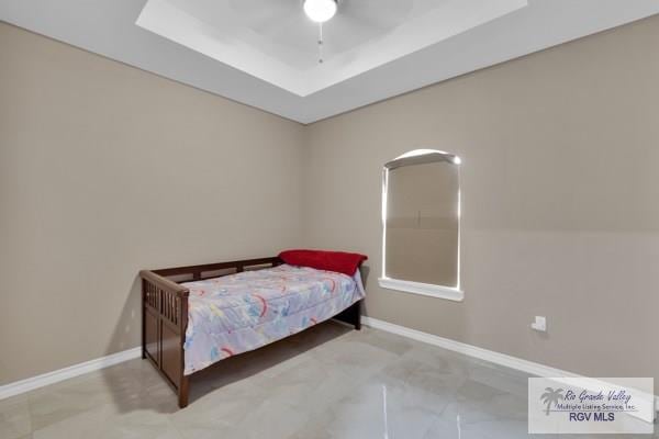 bedroom with a tray ceiling, baseboards, and a ceiling fan