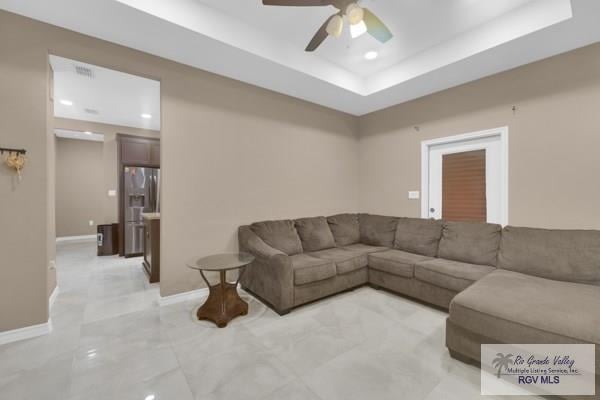 living room with visible vents, baseboards, a tray ceiling, recessed lighting, and a ceiling fan