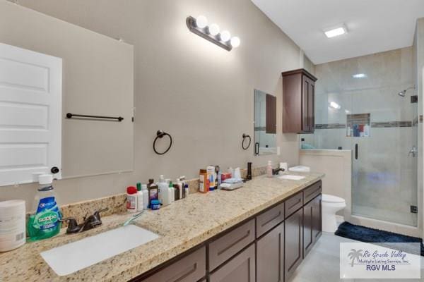 full bathroom with a sink, toilet, a stall shower, and double vanity