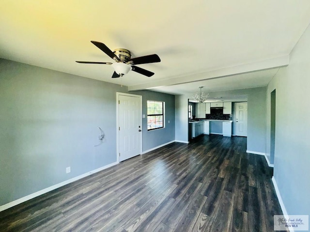 unfurnished living room with ceiling fan with notable chandelier and dark hardwood / wood-style floors