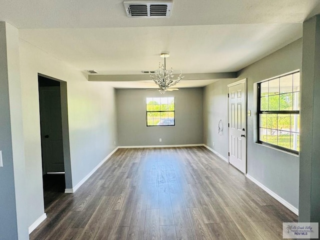 unfurnished dining area featuring dark wood-type flooring and a notable chandelier