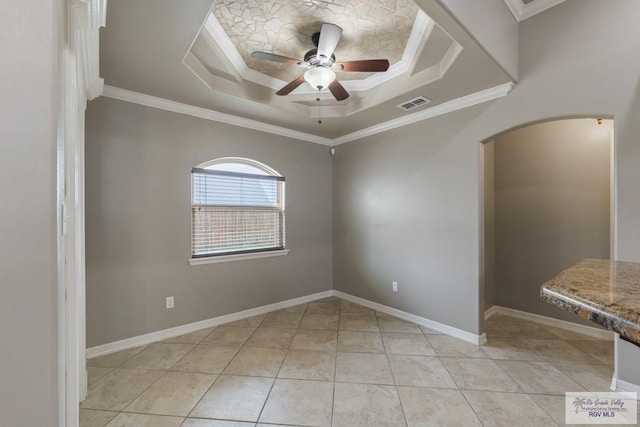 tiled spare room featuring a tray ceiling, ornamental molding, and ceiling fan