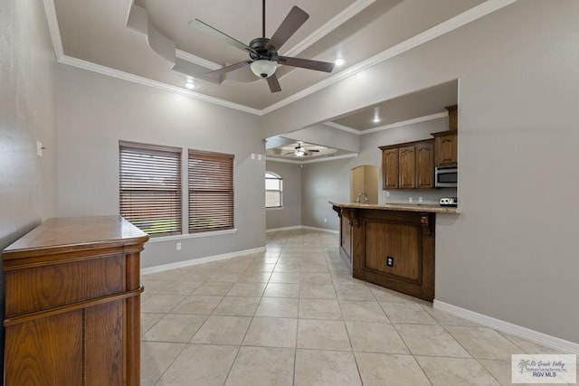 kitchen featuring a raised ceiling, light tile patterned flooring, crown molding, and ceiling fan