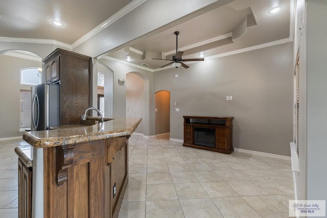 kitchen featuring a raised ceiling, ceiling fan, light tile patterned flooring, and stainless steel refrigerator