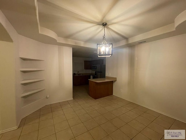 interior space featuring sink, a raised ceiling, a notable chandelier, and light tile patterned flooring