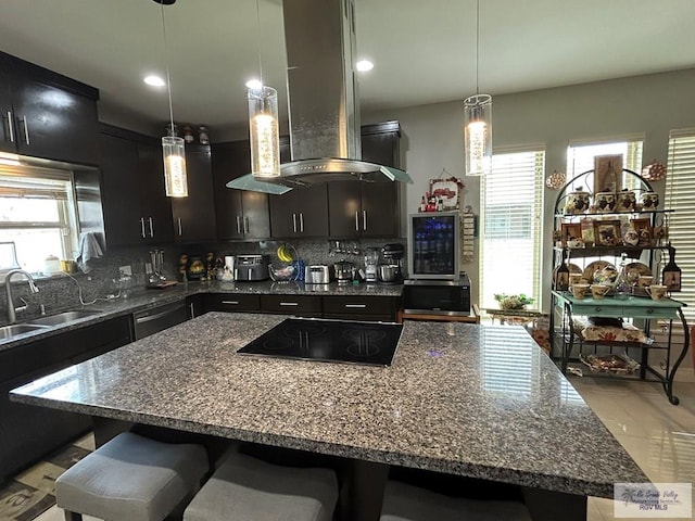 kitchen featuring island range hood, a sink, stovetop, a kitchen bar, and backsplash