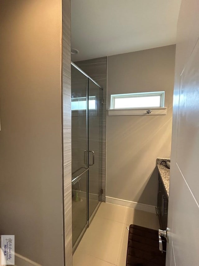 full bathroom featuring a stall shower, tile patterned flooring, baseboards, and vanity