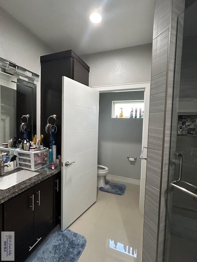 bathroom featuring toilet, vanity, a shower with door, and baseboards