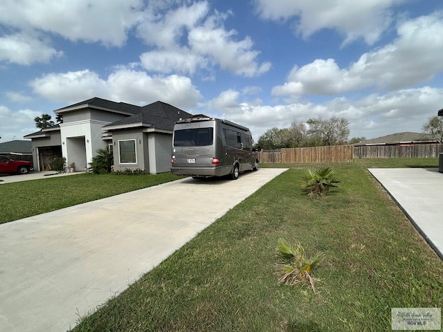 view of home's exterior with concrete driveway, stucco siding, fence, and a lawn