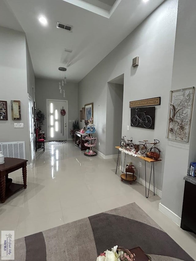 foyer entrance featuring high vaulted ceiling, visible vents, and baseboards