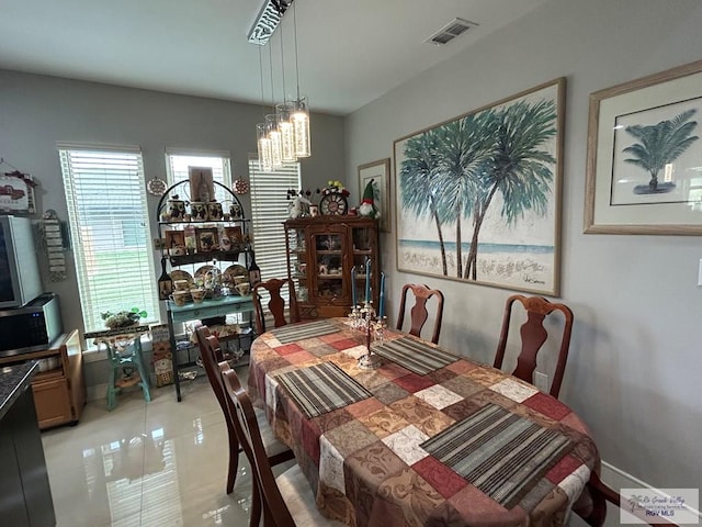 dining space with an inviting chandelier, baseboards, light tile patterned floors, and visible vents