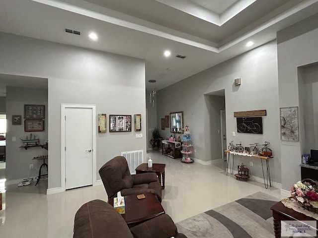 living area featuring a towering ceiling, baseboards, visible vents, and recessed lighting