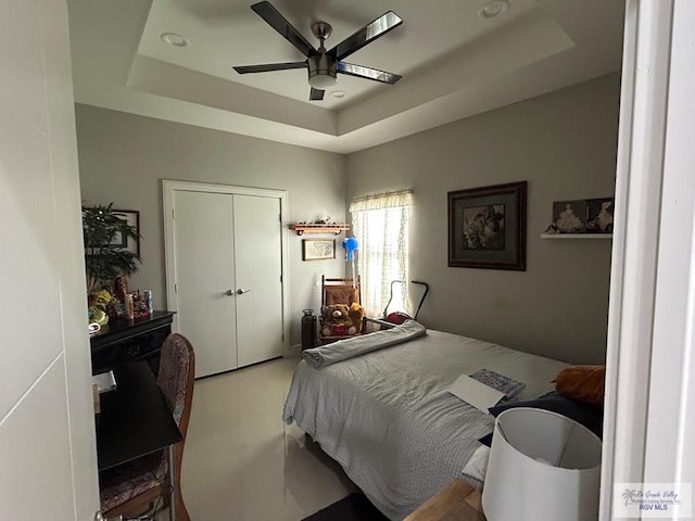 bedroom featuring a closet, a raised ceiling, and ceiling fan