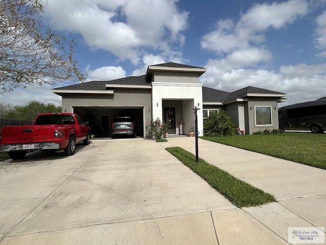 prairie-style home with roof with shingles, stucco siding, concrete driveway, an attached garage, and a front lawn