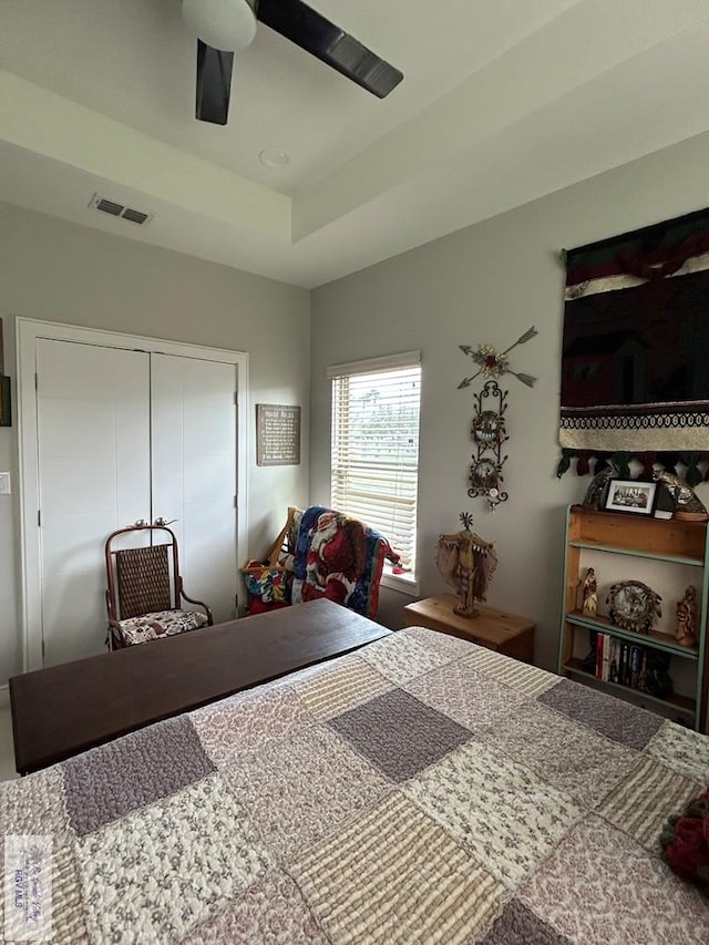 bedroom featuring a ceiling fan, visible vents, a raised ceiling, and a closet