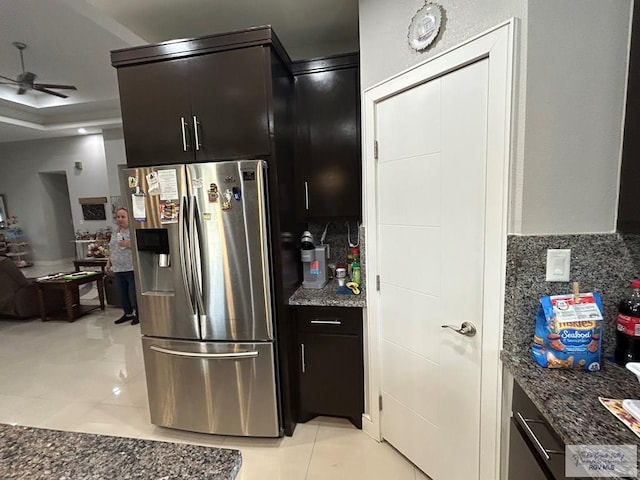 kitchen featuring light tile patterned floors, stainless steel fridge, tasteful backsplash, a ceiling fan, and dark stone countertops