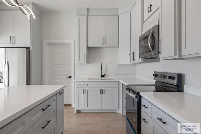 kitchen featuring appliances with stainless steel finishes, light hardwood / wood-style floors, sink, and white cabinets