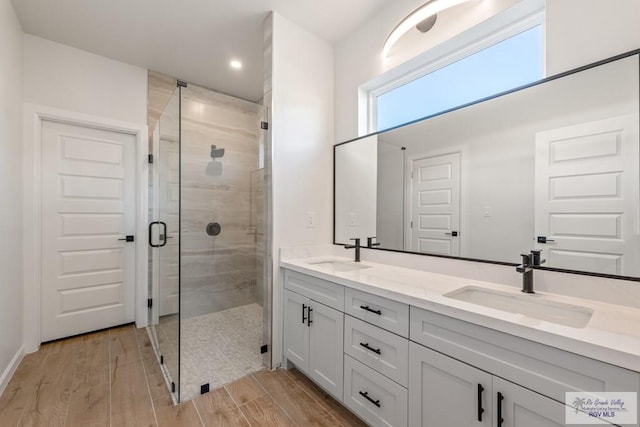 bathroom with hardwood / wood-style flooring, vanity, and a shower with shower door