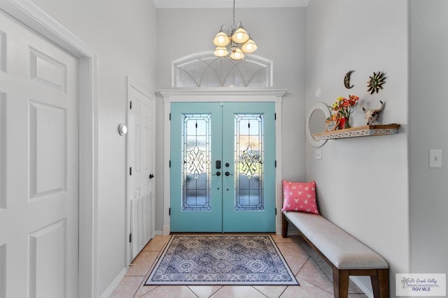 tiled foyer entrance with a notable chandelier and french doors