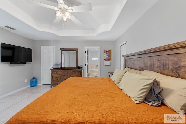 unfurnished bedroom with ceiling fan, light tile patterned flooring, a raised ceiling, and connected bathroom